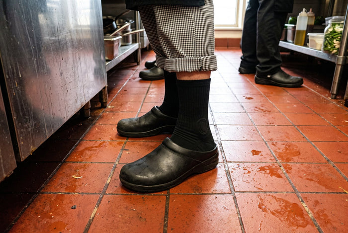 Chaussettes HARDSEN portées avec des sabots sur le carrelage d'une cuisine